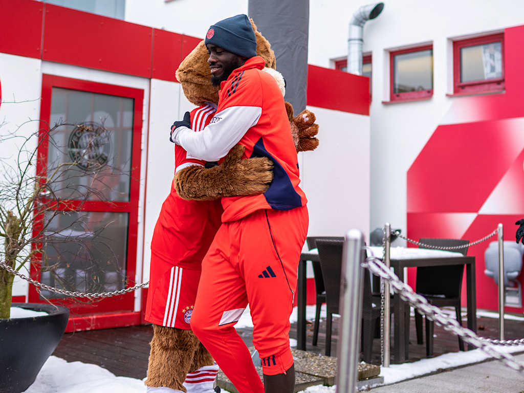 Dayot Upamecano umarmt Maskottchen Berni vor dem öffentlichen Training des FC Bayern vor Fans