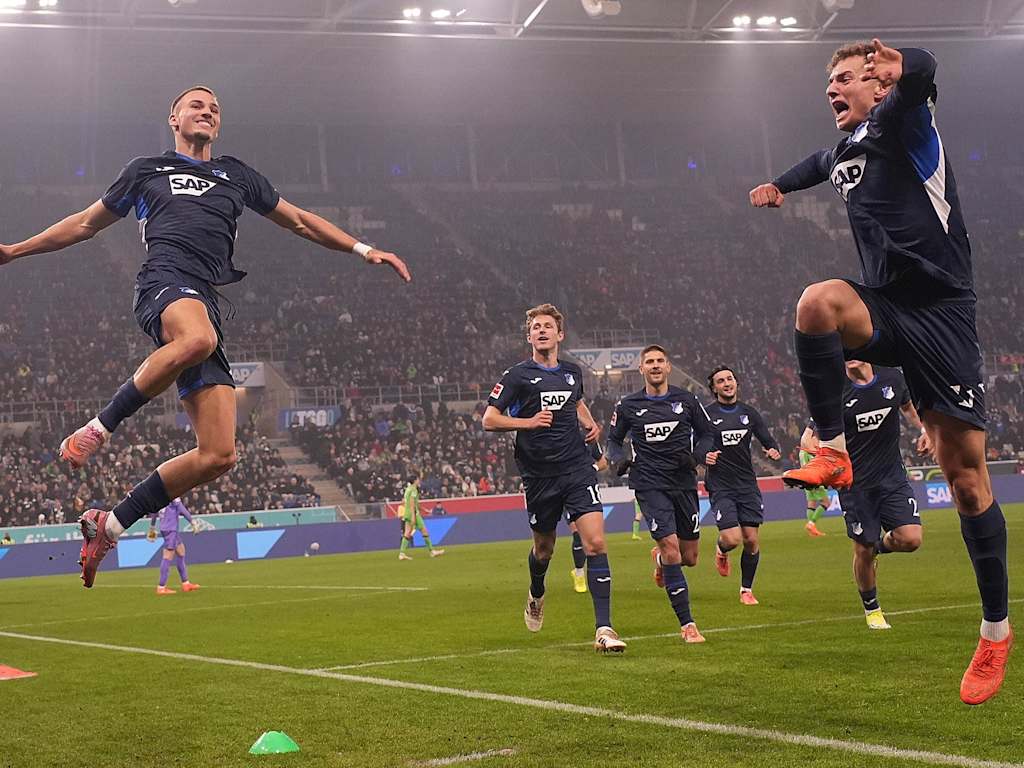 Tim Lemperle and Fisnik Asllani leap into the air in blue Hoffenheim jerseys.