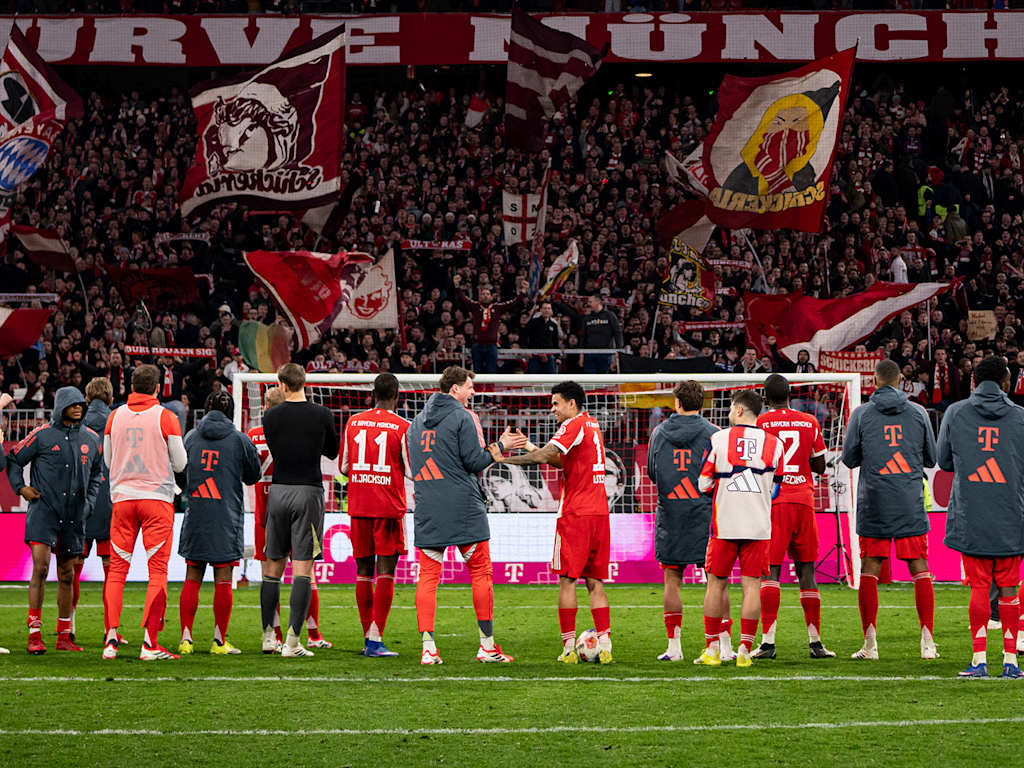 Spieler des FC Bayern jubeln mit den Fans vor der Südkurve.