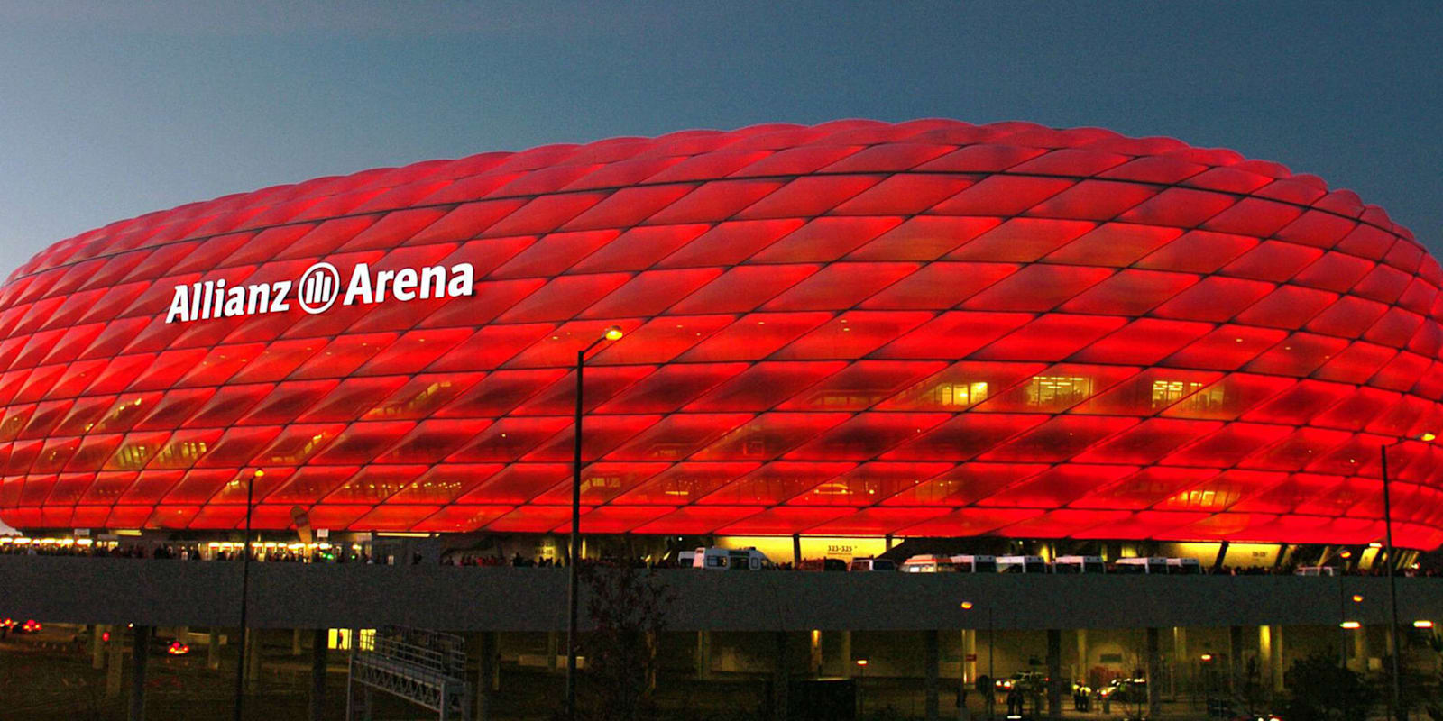 Die Allianz Arena leuchtet rot in der Dämmerung.