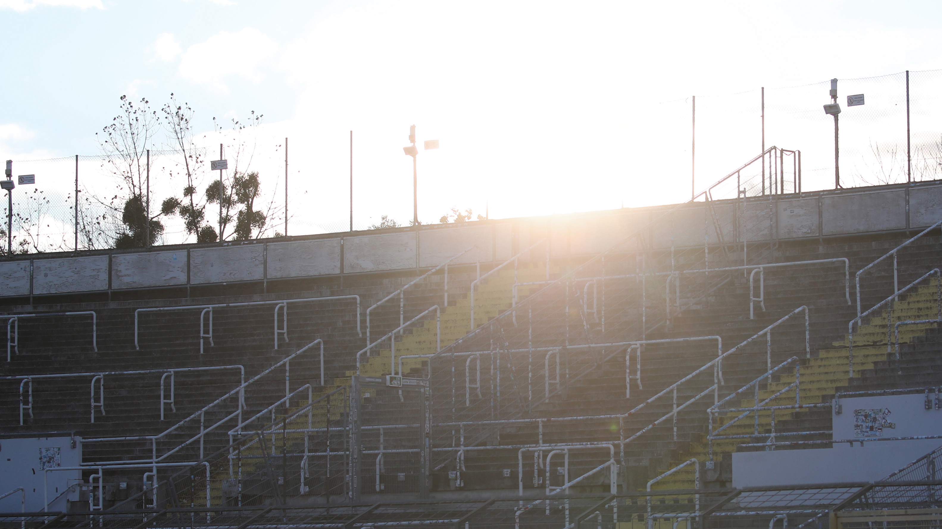 Die Sonne geht hinter der Tribüne am Grünwalder Stadion unter.