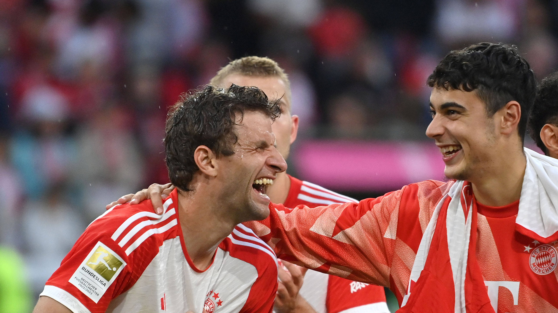 Thomas Müller und Aleksandar Pavlović lachen gemeinsam nach einem Sieg des FC Bayern.