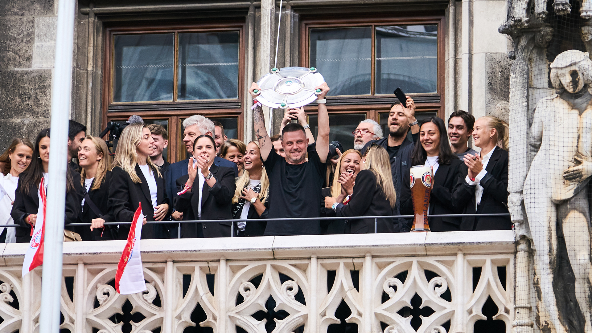 Coach Alexander Straus holds aloft the Meisterschale to the 2,500 fans on Marienplatz.