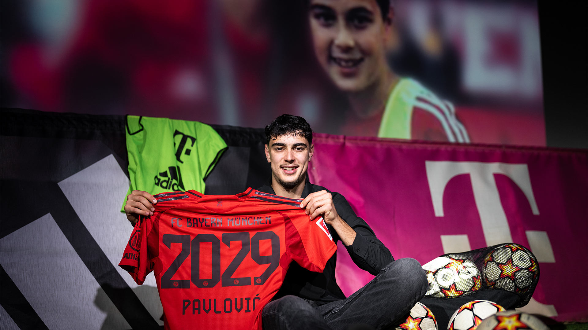 Pavlovic with an FC Bayern shirt marked 2029 in front of a picture from his youth days