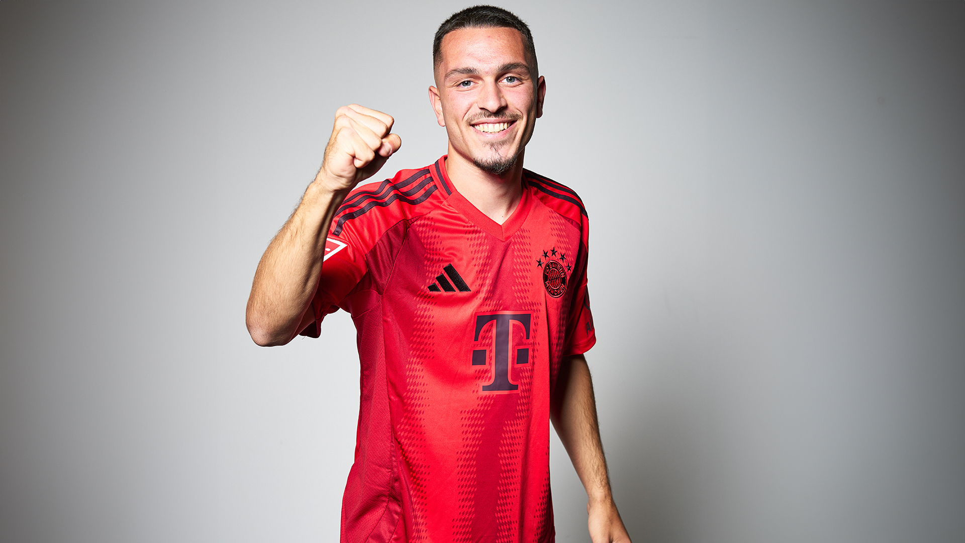 After his contract extension, Arijon Ibrahimovic holds up an FC Bayern jersey with the number 2027.