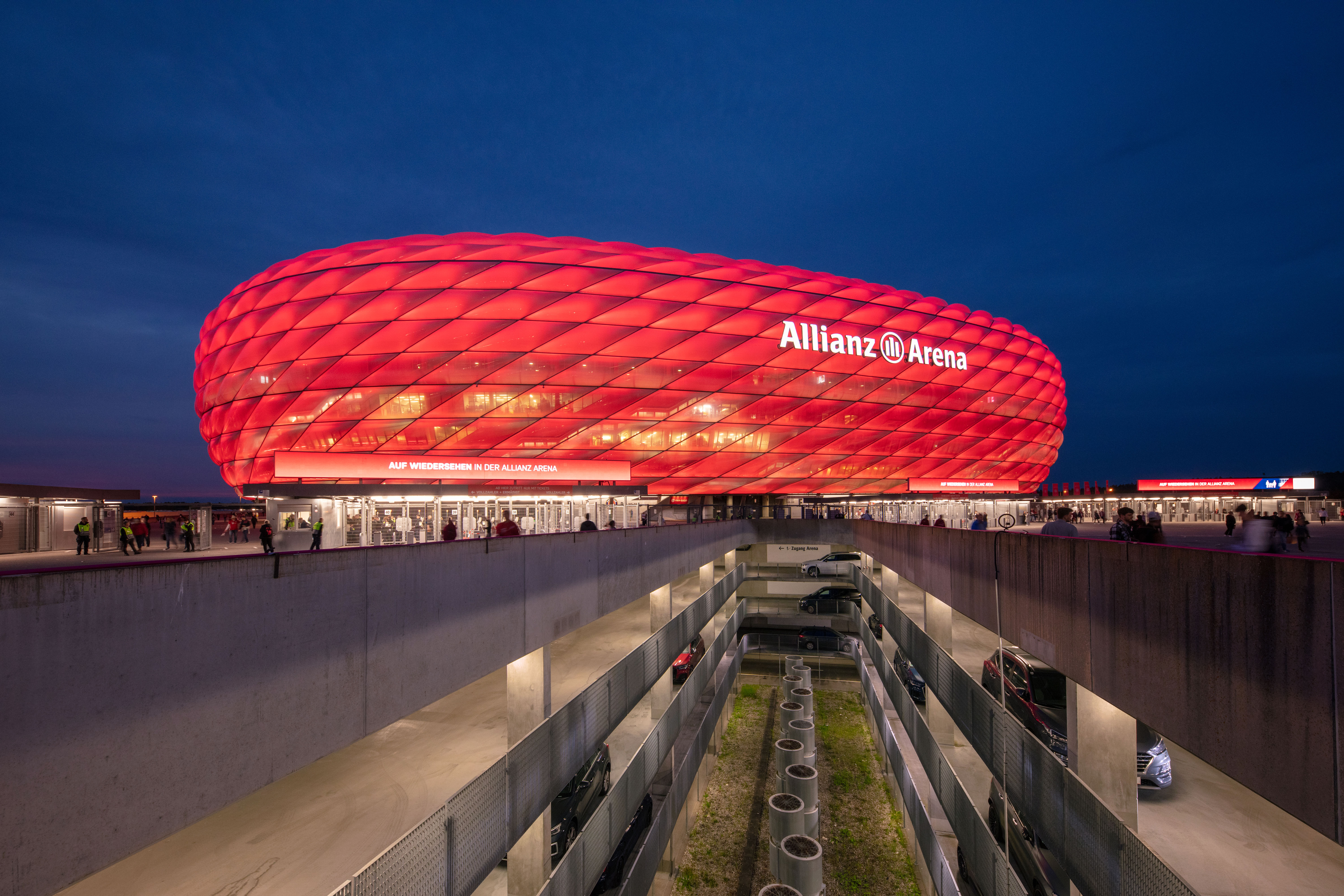 Rot erleuchtete Allianz Arena und Parkhäuser