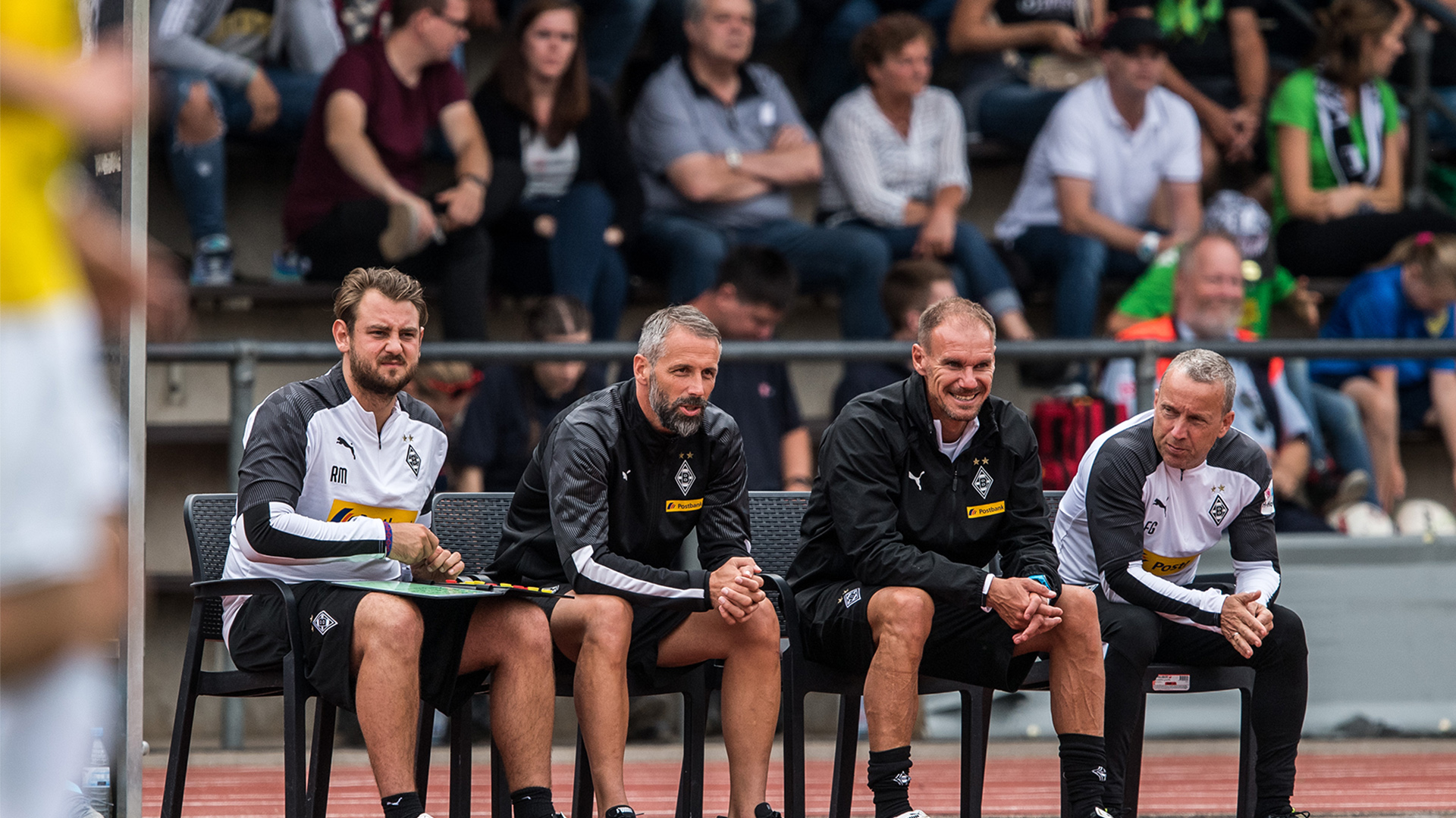 Rene Maric, Marco Rose, Alexander Zickler und Frank Geideck sitzen auf der Trainerbank bei einem Vorbereitungsspiel von Borussia Mönchengladbach.