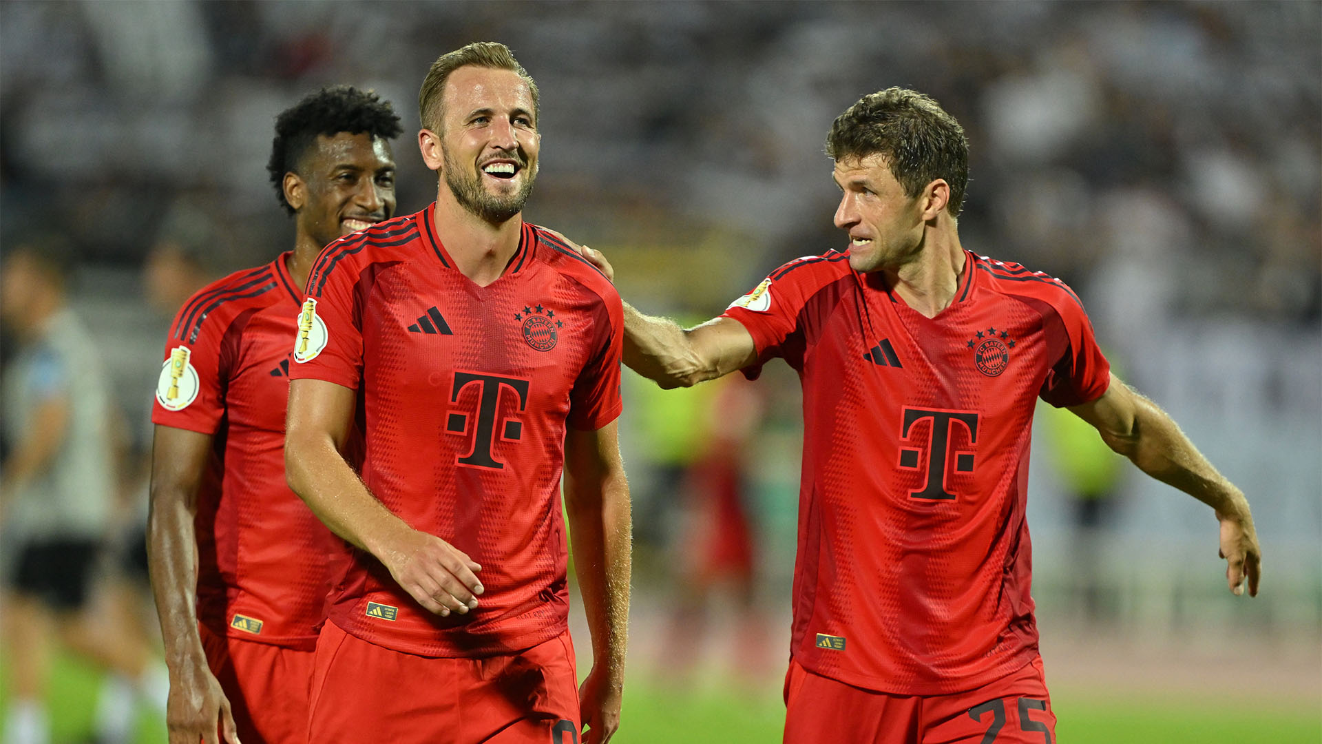 Thomas Müller pats the smiling Harry Kane on the shoulder.