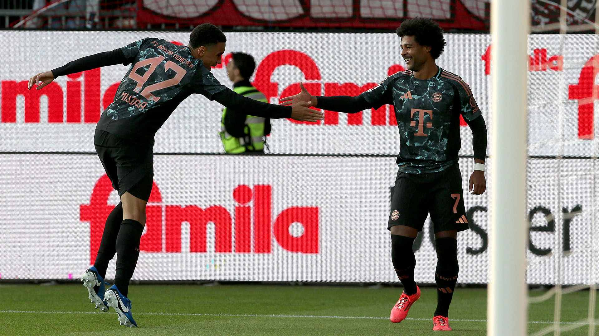 Jamal Musiala y Serge Gnabry chocan las manos tras marcar en el partido contra el Kiel.