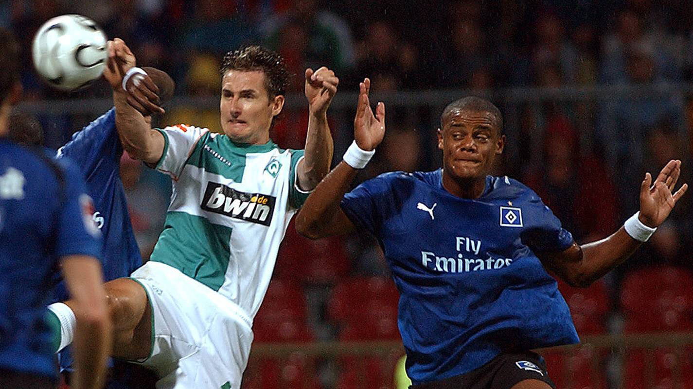 Vincent Kompany and Guy Demel of Hamburger SV challenge Bremen's Miroslav Klose in the air.