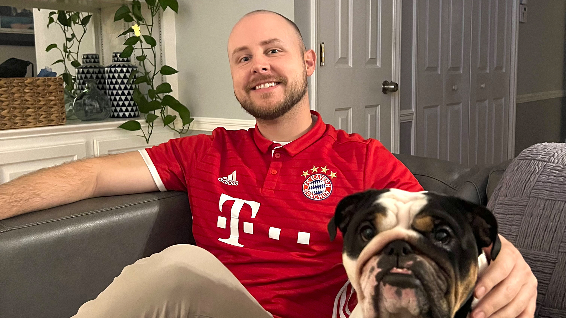 FC Bayern-Fan Kyle sitzt auf einer Couch neben seinem Hund.