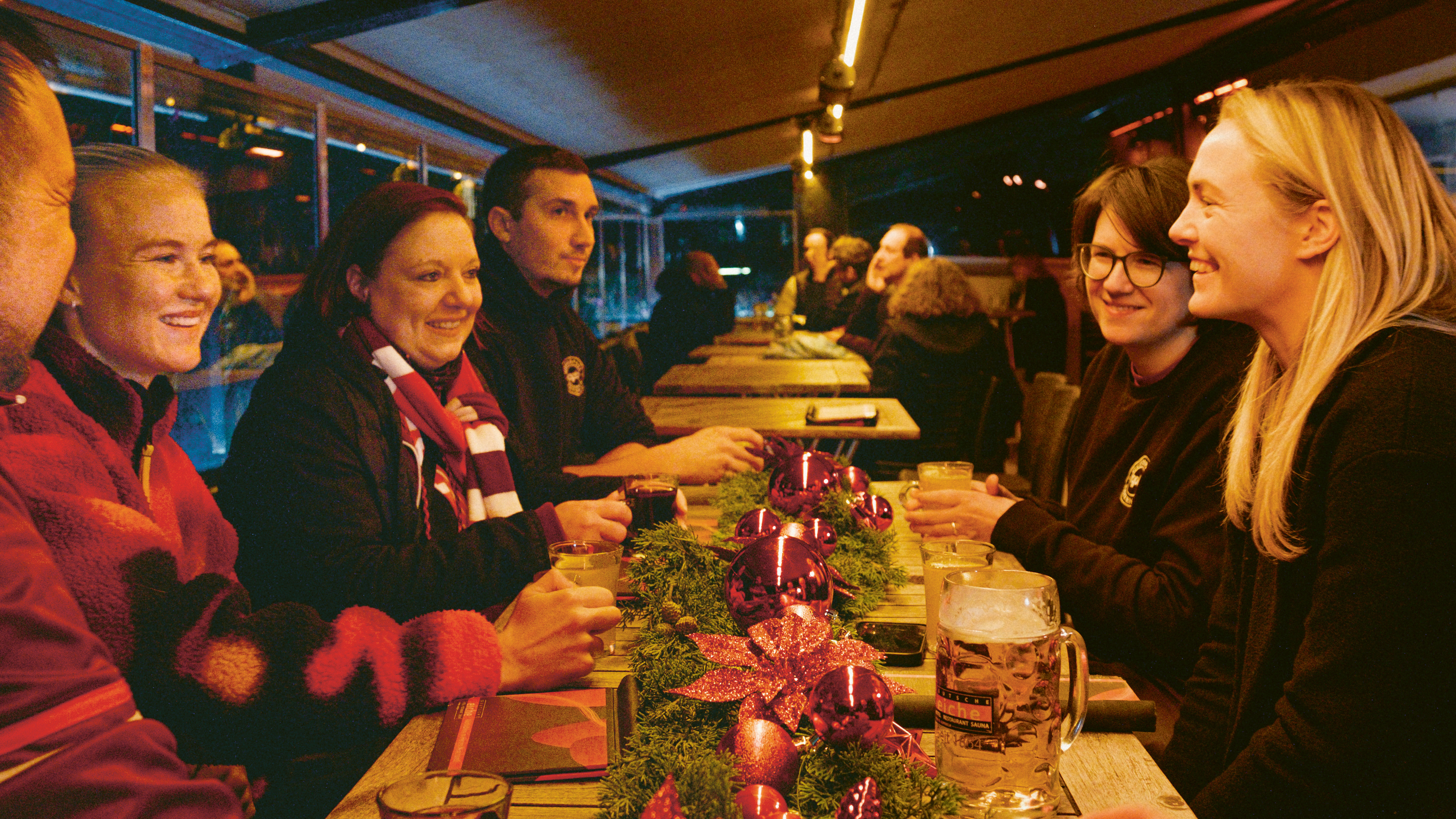 Pernille Harder y Magdalena Eriksson se sientan en una mesa navideña con miembros del club de fans del FC Bayern "QUEERPASS BAYERN"