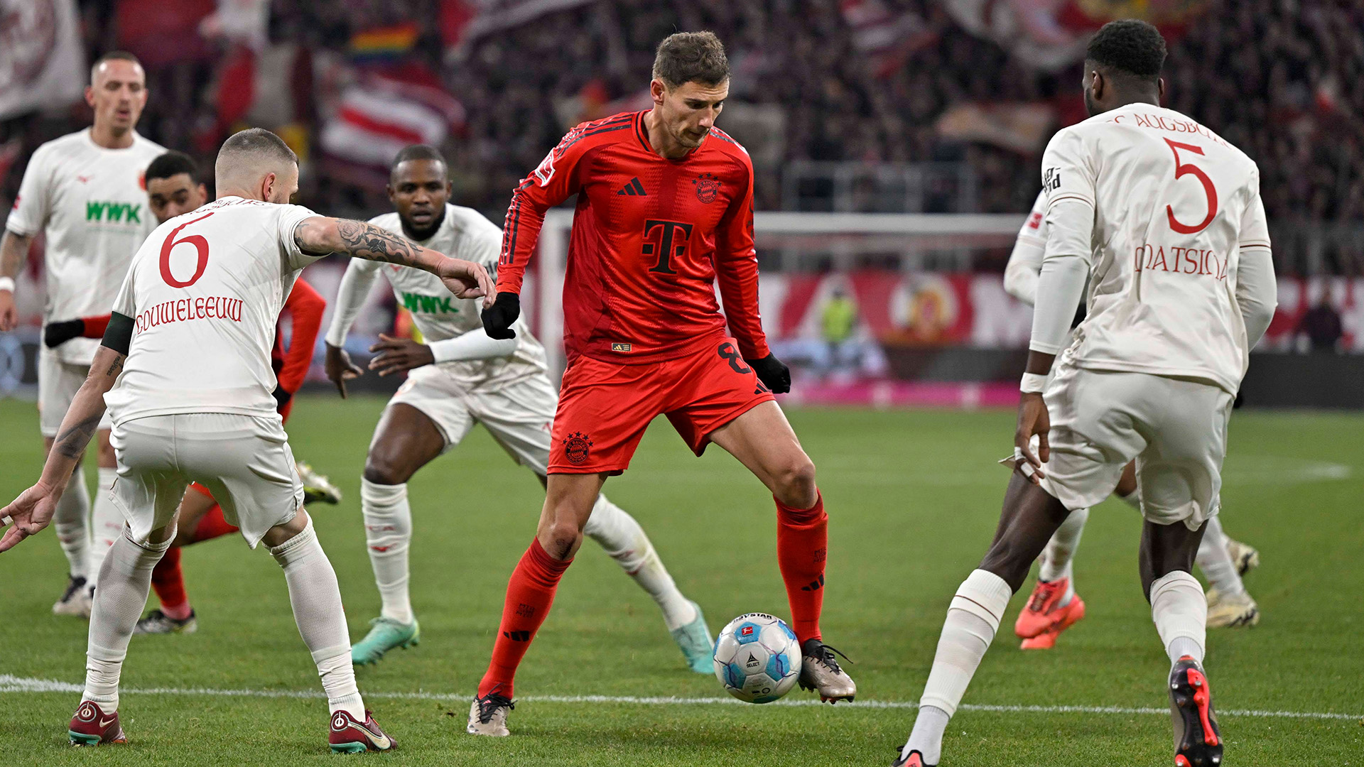 Leon Goretzka surrounded by Augsburg defenders.