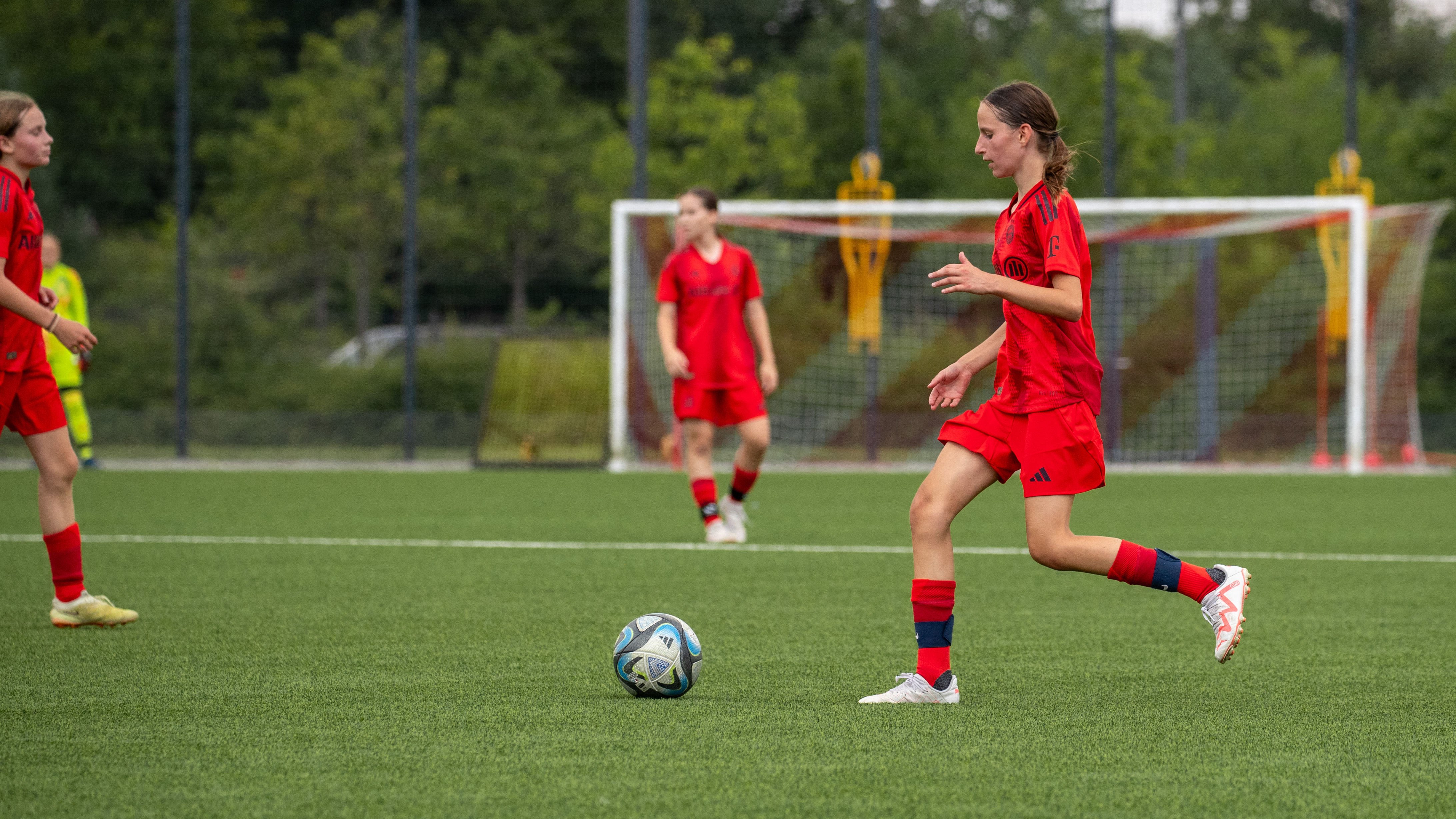 Spielerin der U15-Juniorinnen im Heimtrikot mit dem Ball am Fuß.