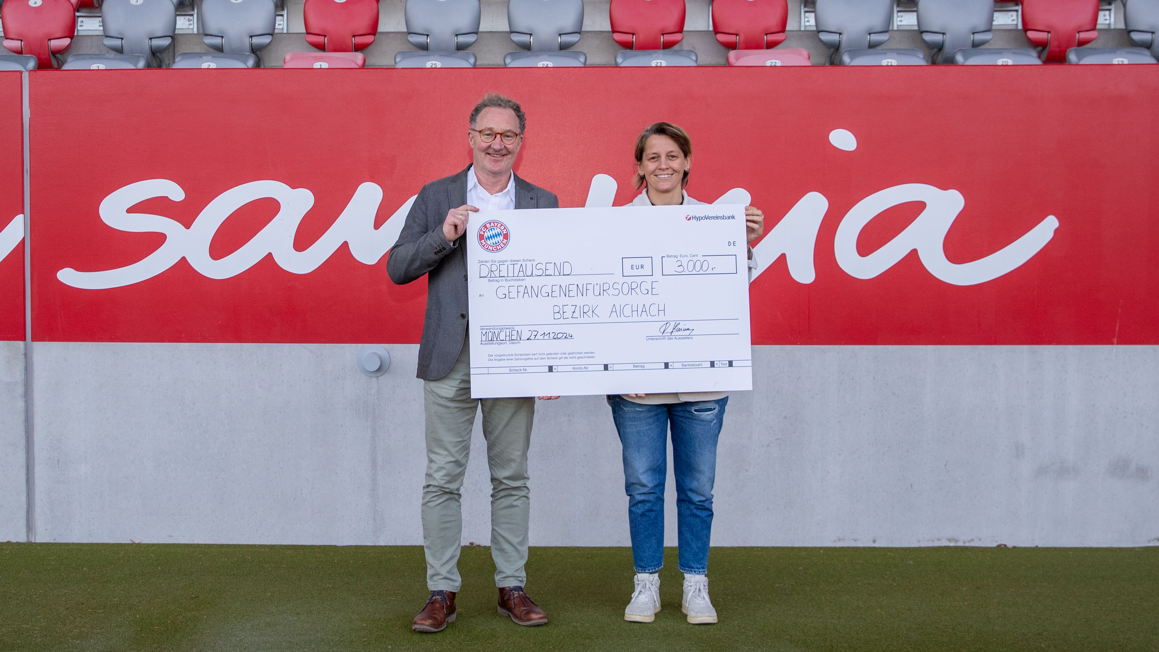 Bianca Rech, Direktorin der FC Bayern Frauen, übergibt einen Spenden-Scheck an den Geschäftsführer des Gefangenenfürsorgevereins Stefan Schrempel.